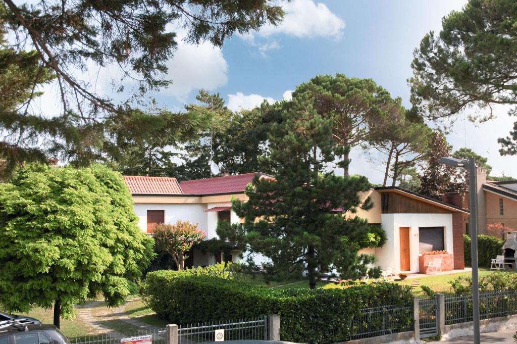 uma casa com árvores e uma cerca em frente em Villa Tre Pini em Lignano Sabbiadoro