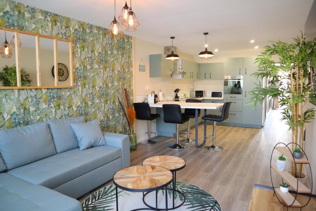 ein Wohnzimmer mit einem Sofa und einer Küche in der Unterkunft L'Escapade Tropicale in Bourbourg