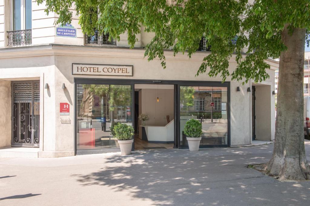 hol hotelowy z dwoma doniczkami przed budynkiem w obiekcie Hôtel Coypel by Magna Arbor w Paryżu