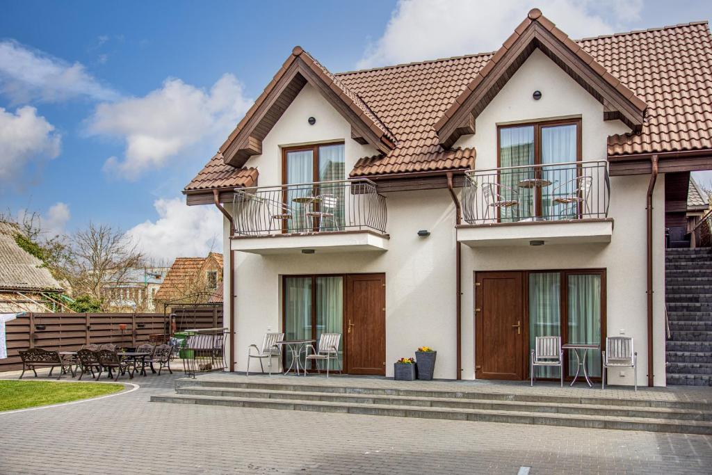 uma casa com varanda, mesas e cadeiras em Palanga Deluxe em Palanga