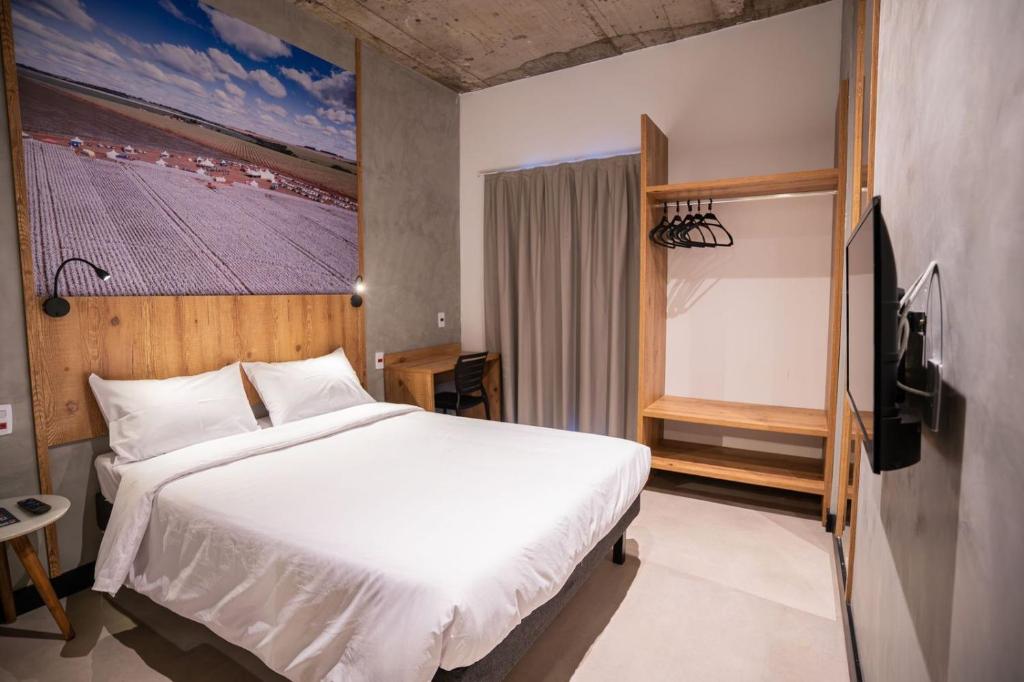 a bedroom with a large white bed and a television at CAMPOS DE HOLAMBRA INN in Paranapanema