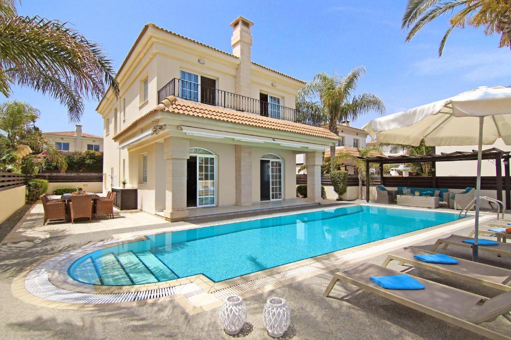 a villa with a swimming pool in front of a house at Villa Oceania - Beachfront in Paralimni
