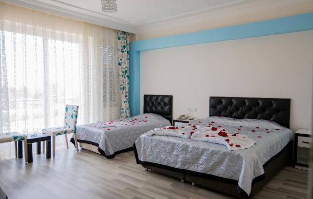 a bedroom with two beds with red flowers on them at Deniz Hotel in Finike