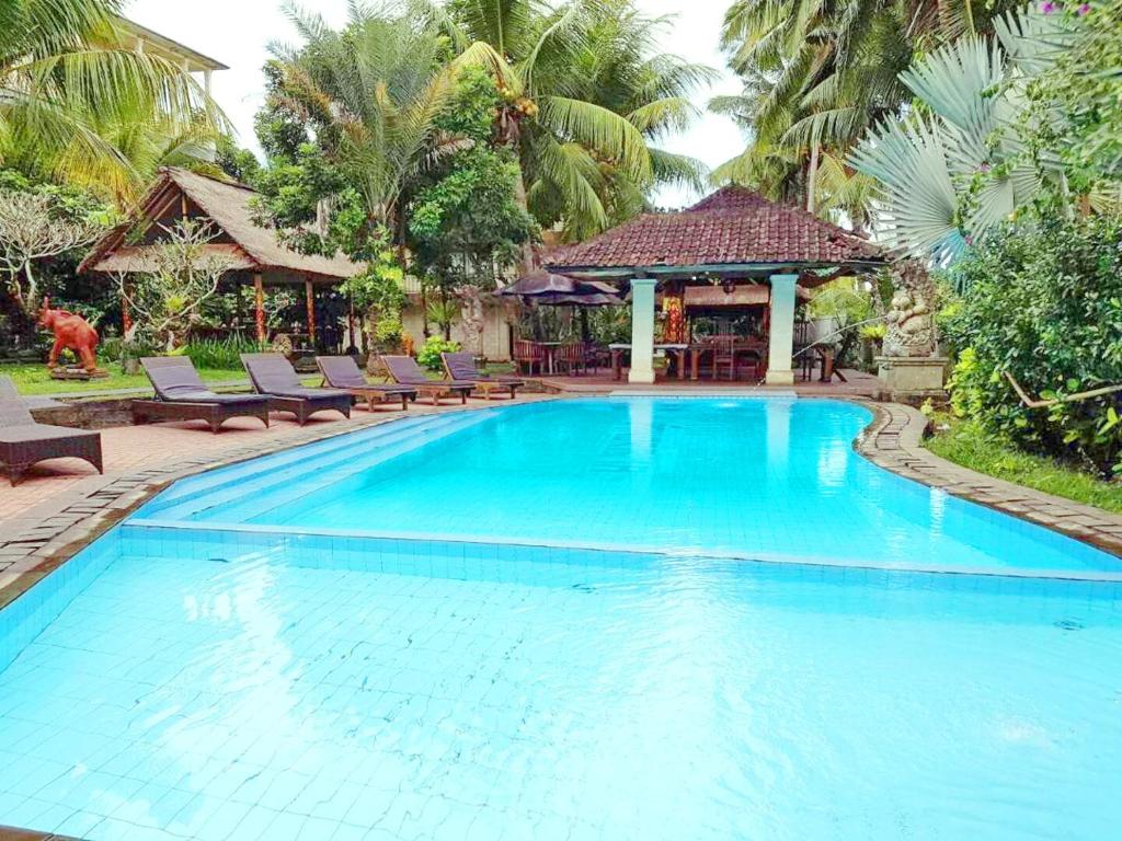 a large blue swimming pool with chairs and a gazebo at Hotel rooms 2 minutes to Monkey Forest in Ubud