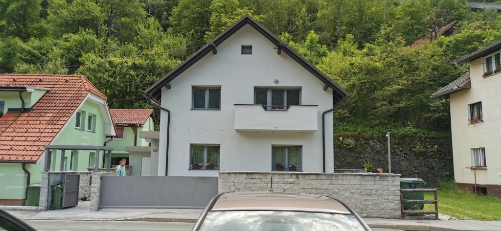 a white house with a black roof on a street at Apartma Sava-Stol in Jesenice
