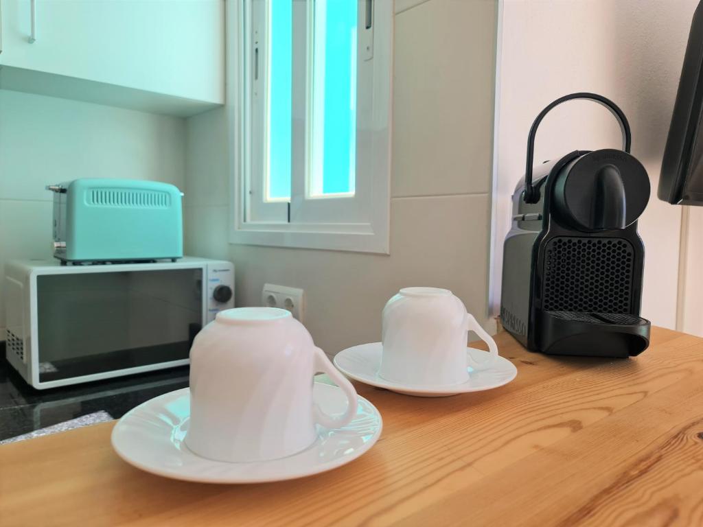 two white cups and saucers on a wooden table at Tabbu ibiza apartments in Playa d'en Bossa