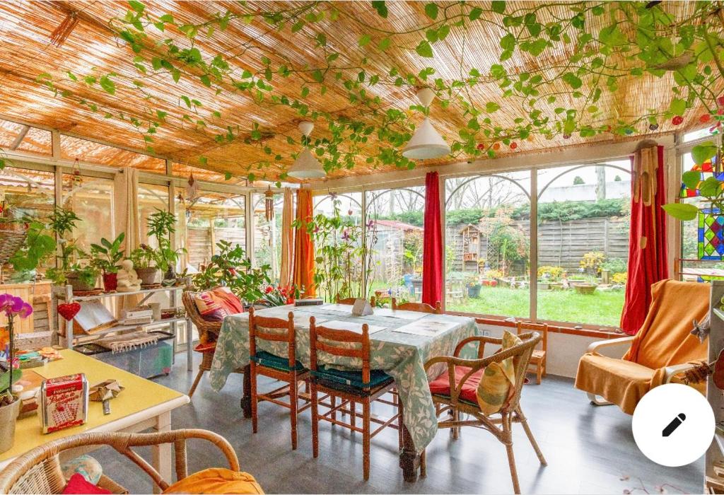 a dining room with a table and chairs and windows at 2 CHAMBRES B&B PRÈS DE L'AÉROPORT ET DU MEETT in Blagnac