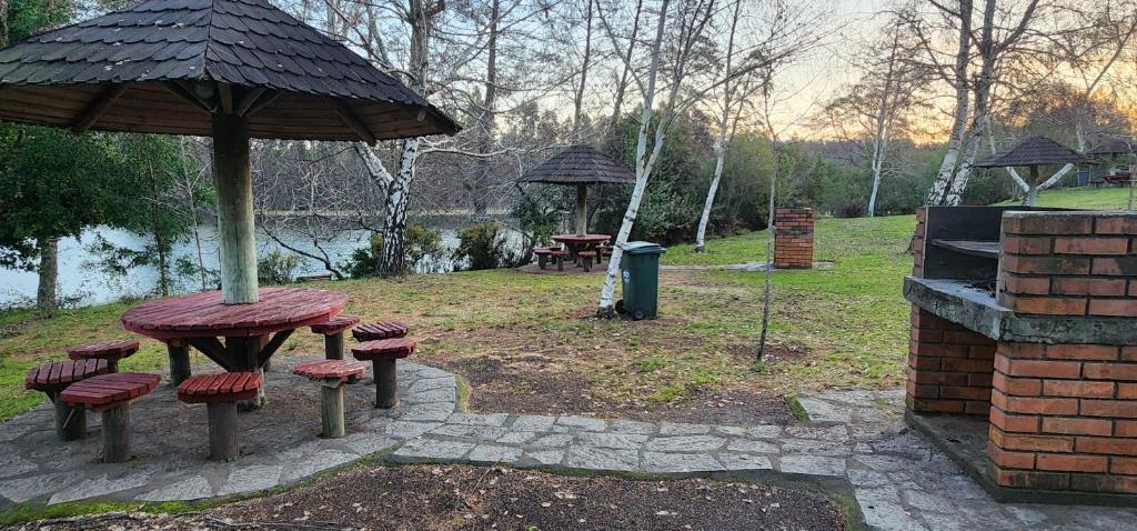 a picnic table and chairs under an umbrella in a park at Hotel y Cabañas Las Mellizas - Caja Los Andes in Los Ángeles
