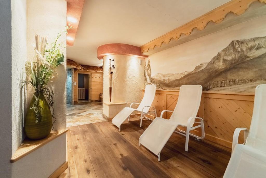 a room with white chairs and a painting on the wall at Hotel Chalet Sas Morin in Pozza di Fassa