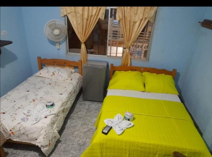 Un dormitorio con una cama amarilla con una flor. en Hospedaje Mirador Grecia en Leticia