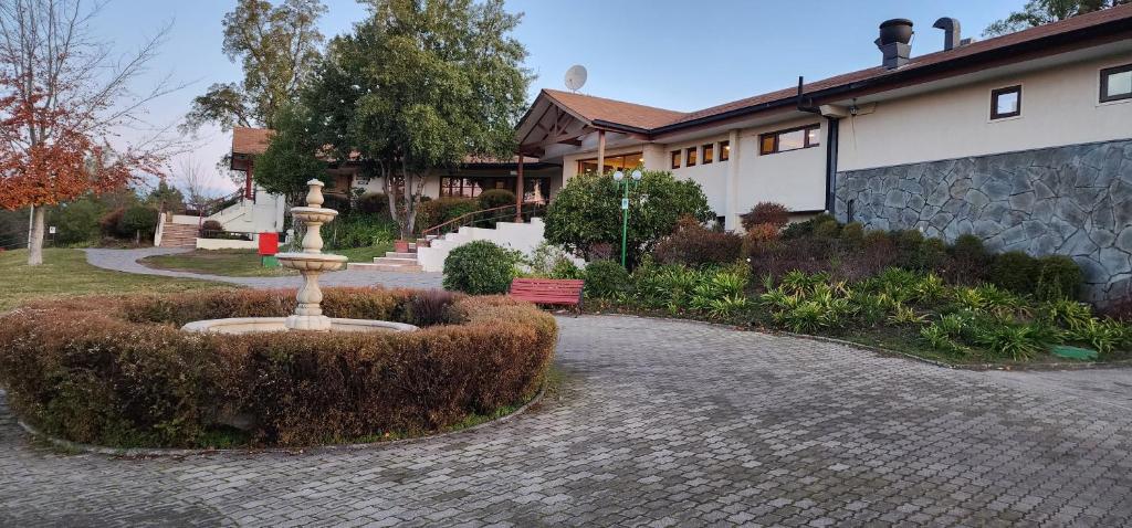 a fountain in the middle of a garden in front of a house at Hotel y Cabañas Las Mellizas - Caja Los Andes in Los Ángeles