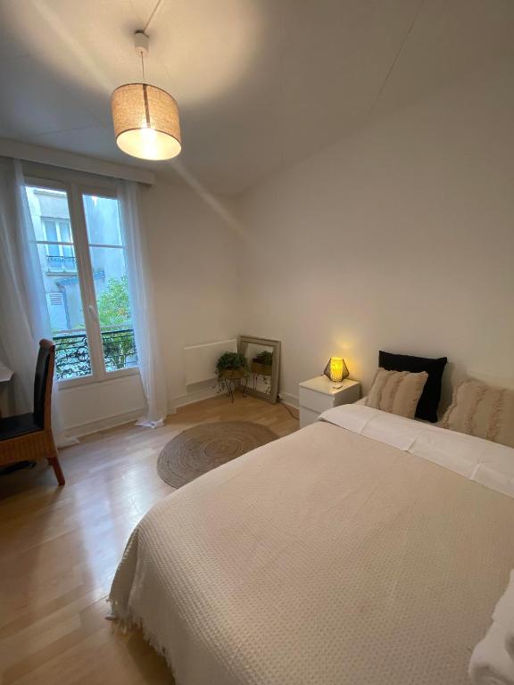 a white bedroom with a large bed and a window at Studio agréable proche Tour Eiffel in Paris
