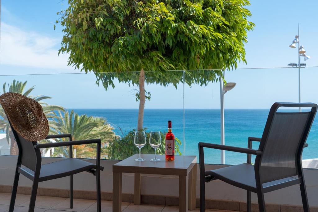 einen Tisch mit 2 Stühlen und eine Flasche Wein in der Unterkunft Sabbia Suites Sea View La Playita in Puerto del Carmen
