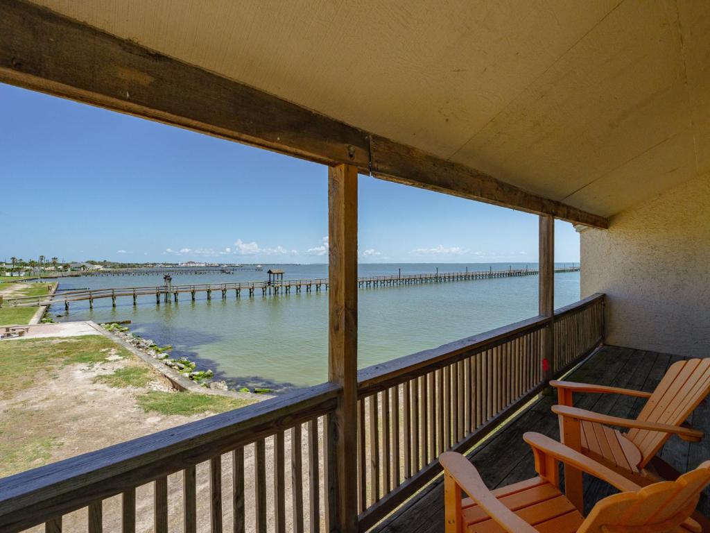 a balcony with chairs and a view of a pier at Bay Breeze Bungalow in Rockport
