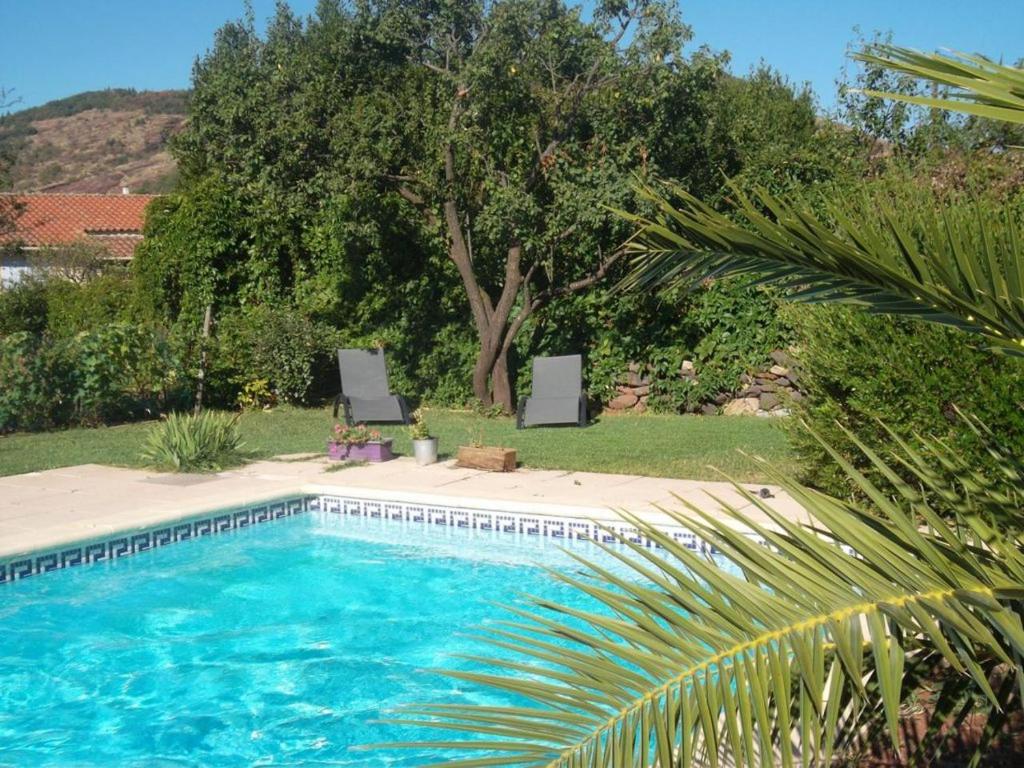 una piscina con due sedie e un albero di Octon, Villa Plain-pied, Piscine a Octon