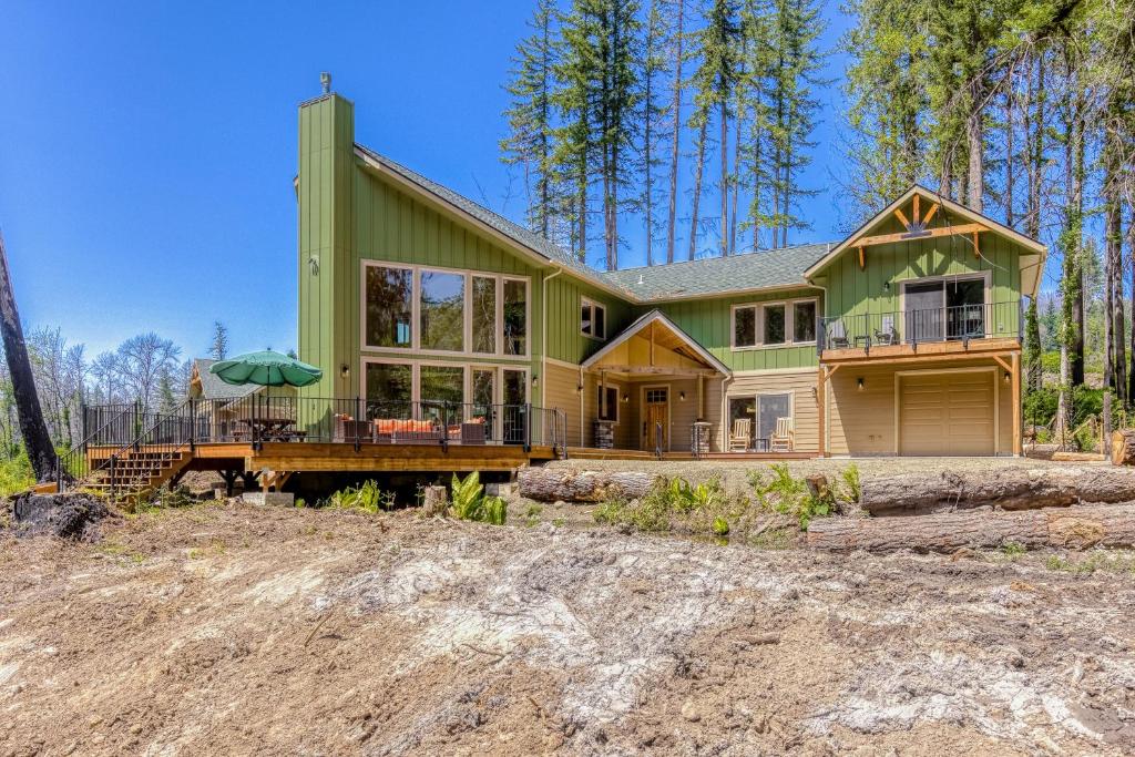 una casa verde en el bosque con un patio en The McKenzie River House, en Vida