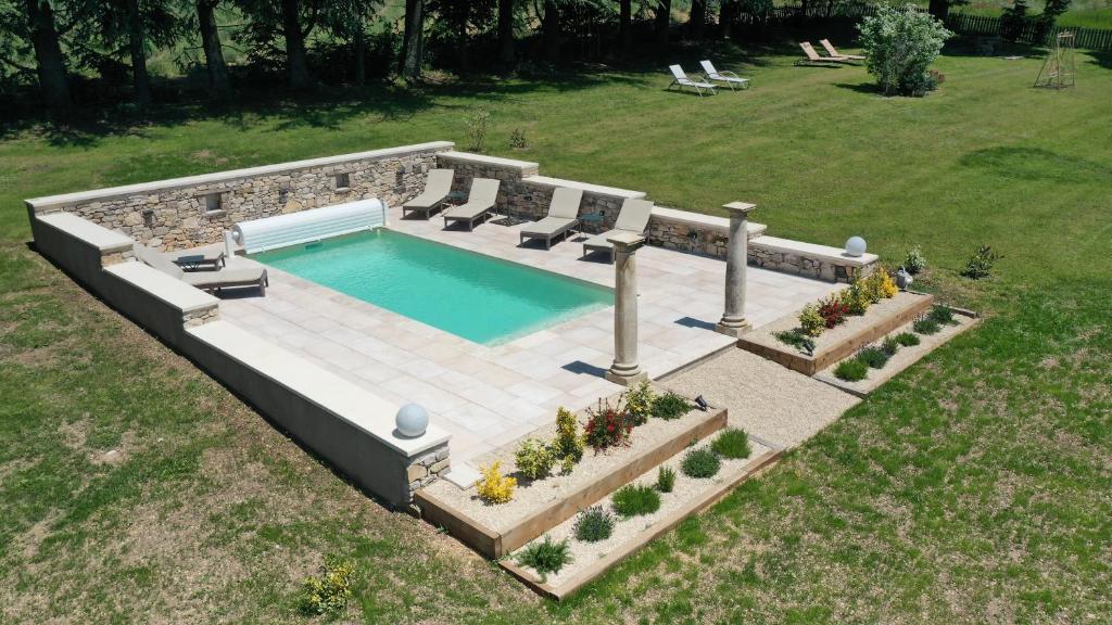 una vista aérea de una piscina con sillas y un jardín en Domaine La Lauren avec piscine chauffée et jacuzzi, en Ferrassières