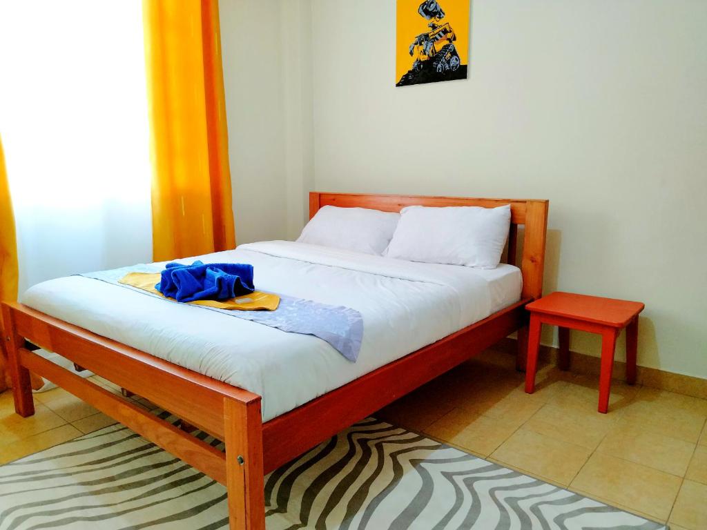 Habitación pequeña con cama y taburete rojo en Cozy Haven en Nanyuki
