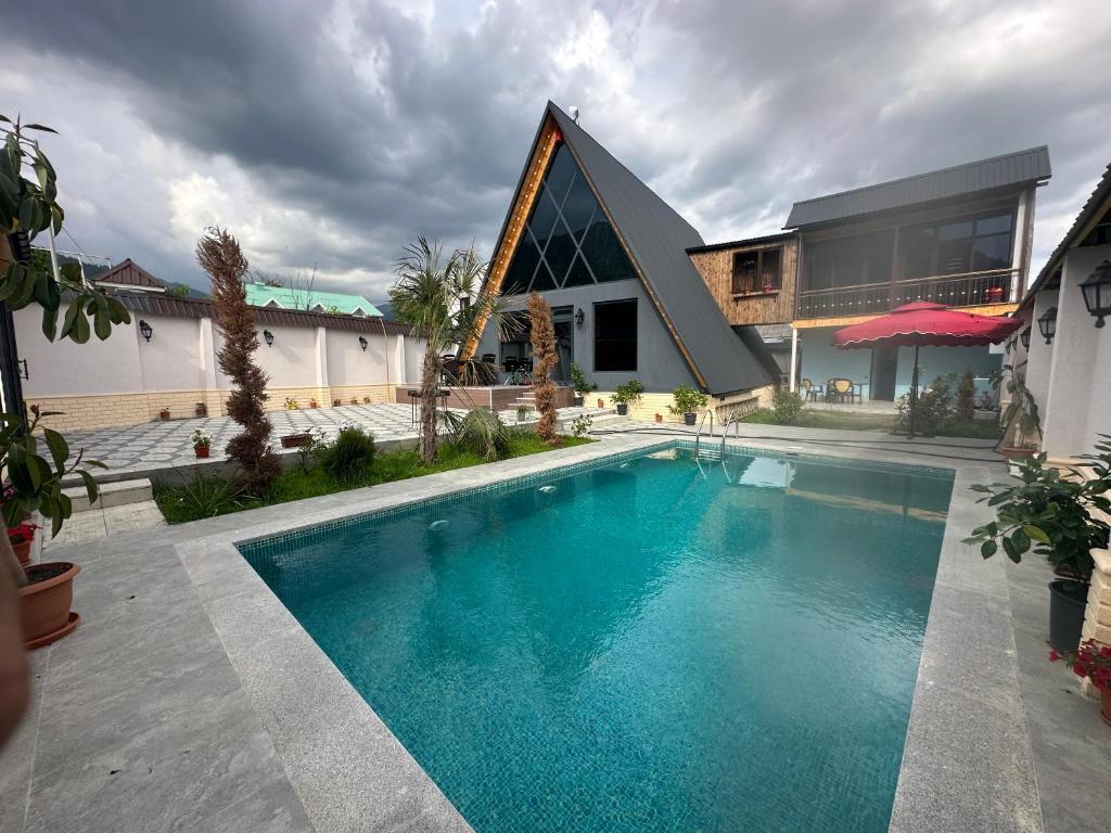 a swimming pool in front of a house with a building at Qafqaz house in Gabala