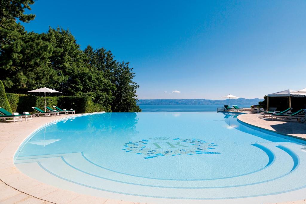 a large swimming pool with a view of the water at Hôtel Royal in Évian-les-Bains