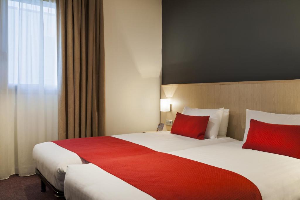 a hotel room with two beds with red pillows at Sure Hotel by Best Western Nantes Beaujoire in Nantes