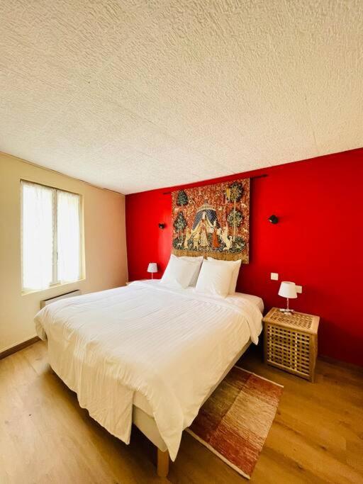 une chambre avec un grand lit avec un mur rouge dans l'établissement Chez-YU au pied de la cité, à Carcassonne
