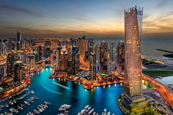 a city skyline with a tall building and a harbor at Luxury Iconic Cayan Tower - Free 5 star Beach Resorts Access! in Dubai