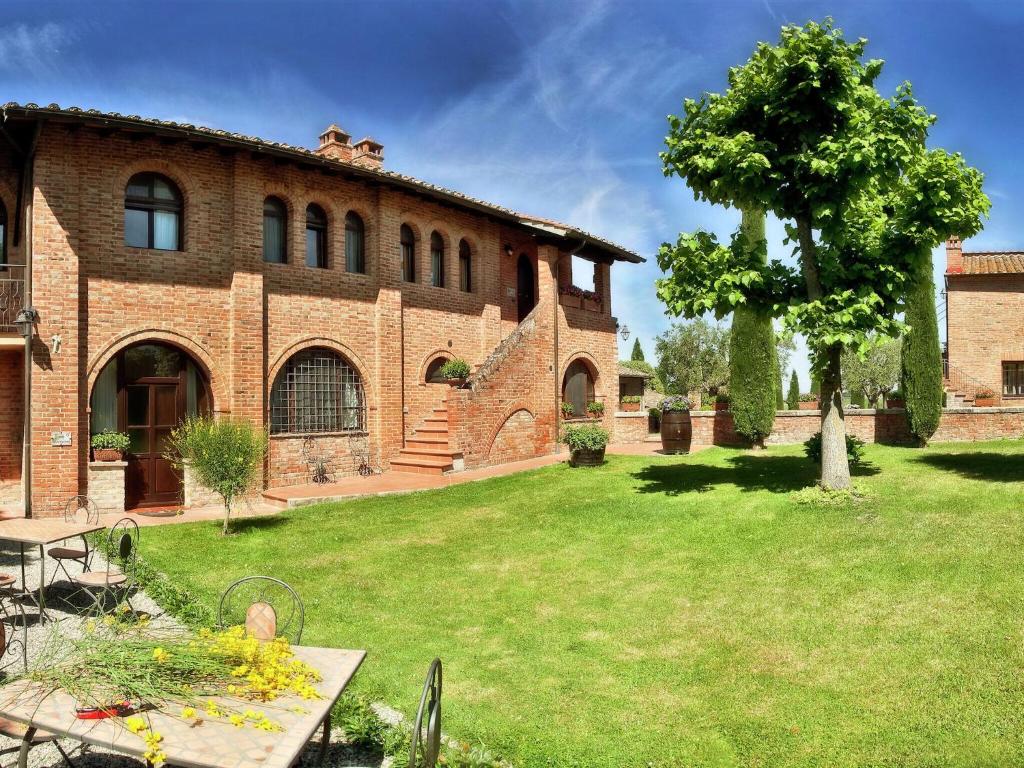 カスティリオーネ・シュル・ラーゴにあるVintage Mansion in Montepulciano with Poolの中庭に木が植えられた大きなレンガ造りの建物