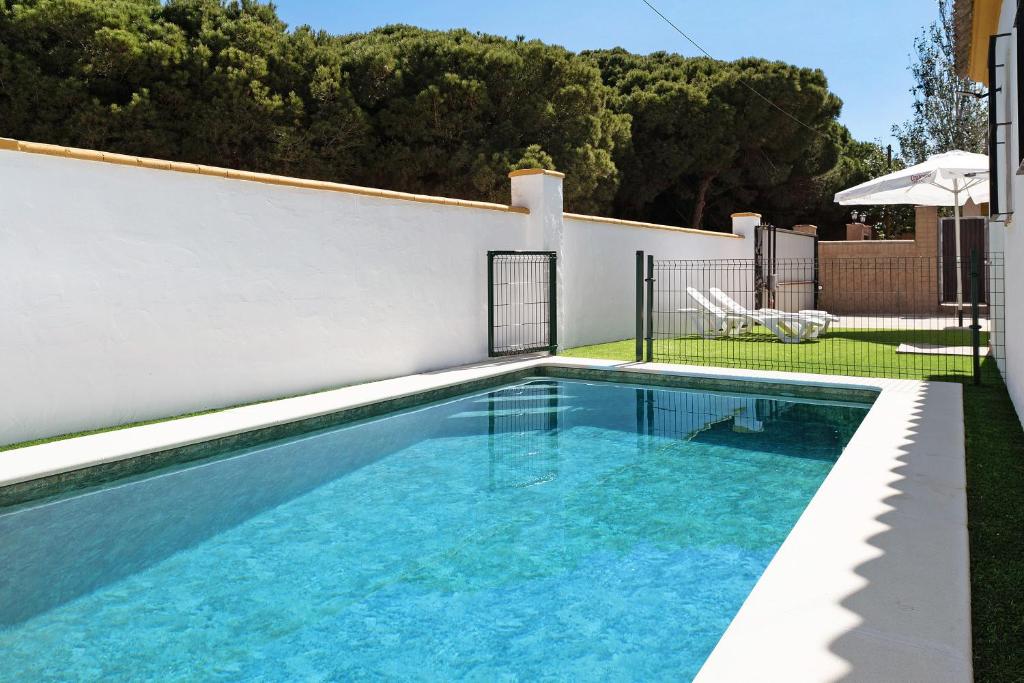 una piscina en un patio trasero con una pared blanca en Casa Paqui 3 en Roche