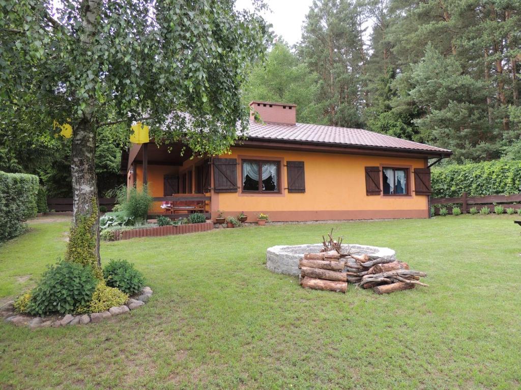 a house with a pile of logs in front of it at Domek letniskowy nad jeziorem Dadaj na Mazurach in Biskupiec