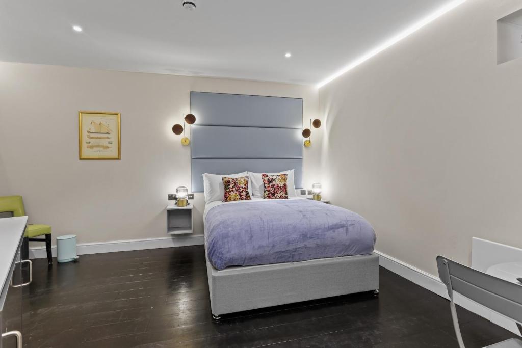 um quarto com uma cama com uma cabeceira azul em Modern Studio Flat em Londres