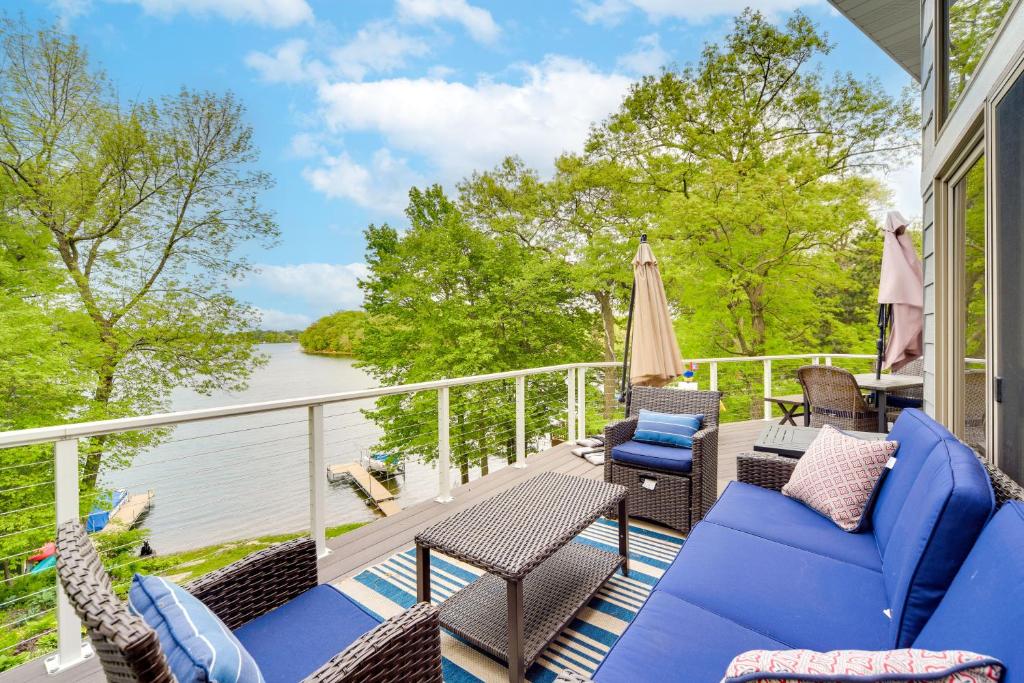 a porch with chairs and tables and a view of the water at Wisconsin Vacation Rental with Fire Pit on Long Lake 