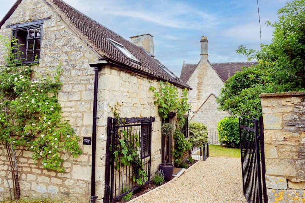 an old stone house with a black gate at Mill House Cottage - Star Stay on The Cotswold Way in Harescombe