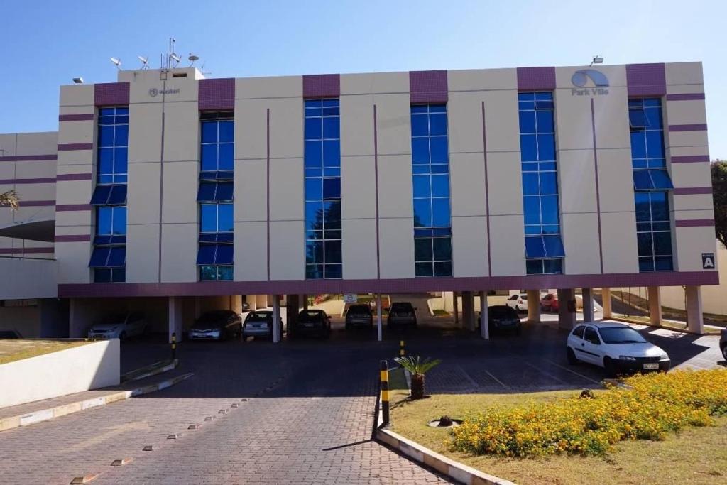 a building with cars parked in a parking lot at Flats Condomínio Park Ville by CentoEdez in Brasília