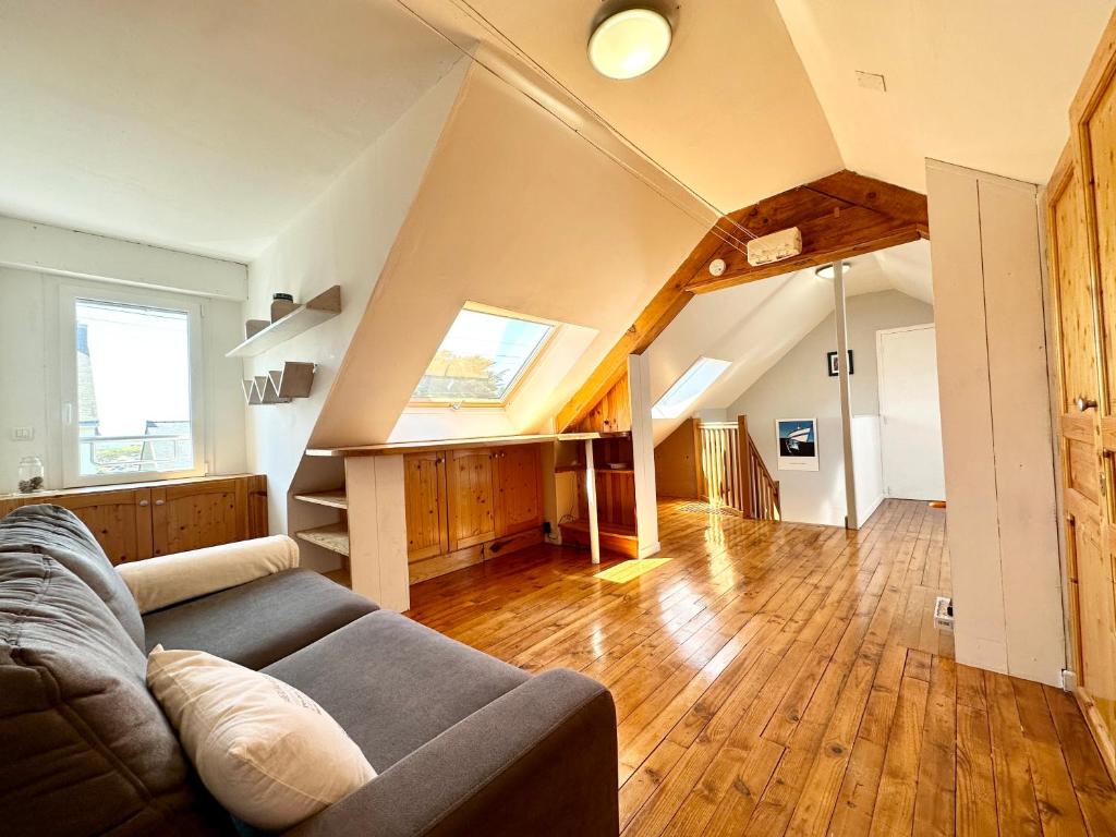 a living room with a couch and wooden floors at Maison de pêcheur - À 200m de la plage in Ploemeur