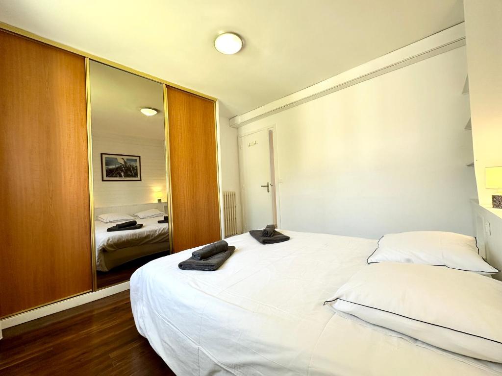a bedroom with a large white bed and a mirror at Maison de pêcheur - À 200m de la plage in Ploemeur