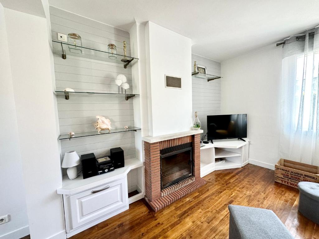 a living room with a fireplace and a tv at Maison de pêcheur - À 200m de la plage in Ploemeur