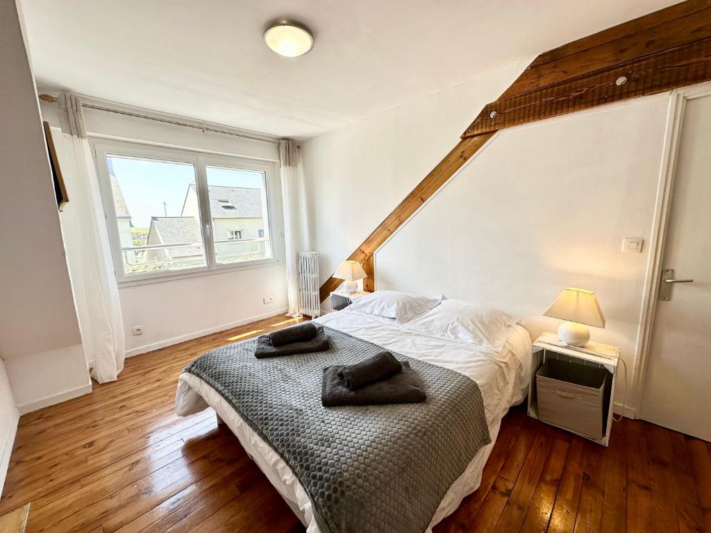 a bedroom with a bed and a large window at Maison de pêcheur - À 200m de la plage in Ploemeur