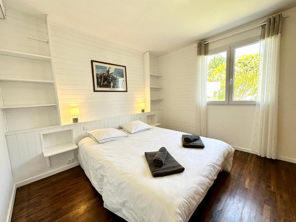 a bedroom with a bed with two black towels on it at Maison de pêcheur - À 200m de la plage in Ploemeur