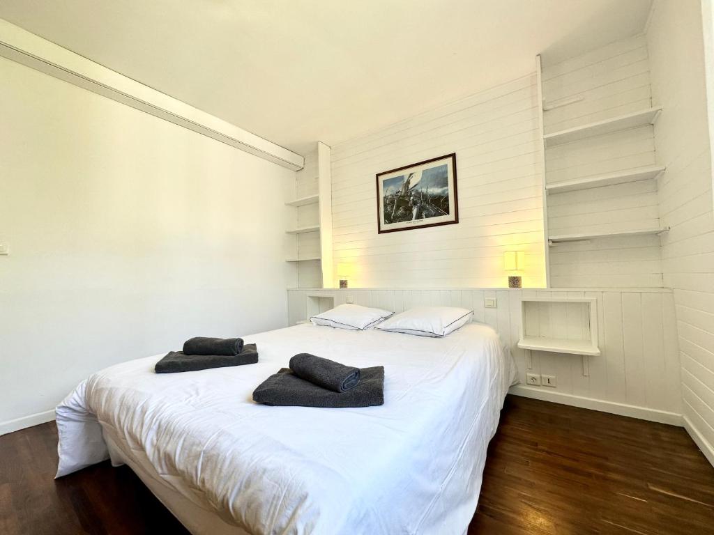 a bedroom with a white bed with two towels on it at Maison de pêcheur - À 200m de la plage in Ploemeur