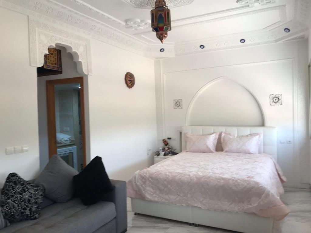 Habitación blanca con cama y sofá en Les portes de l'atlas, en Fez