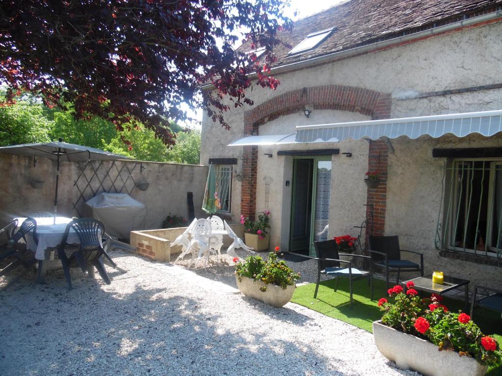 a backyard of a house with a table and chairs at Le clos des tuileries in Montholon