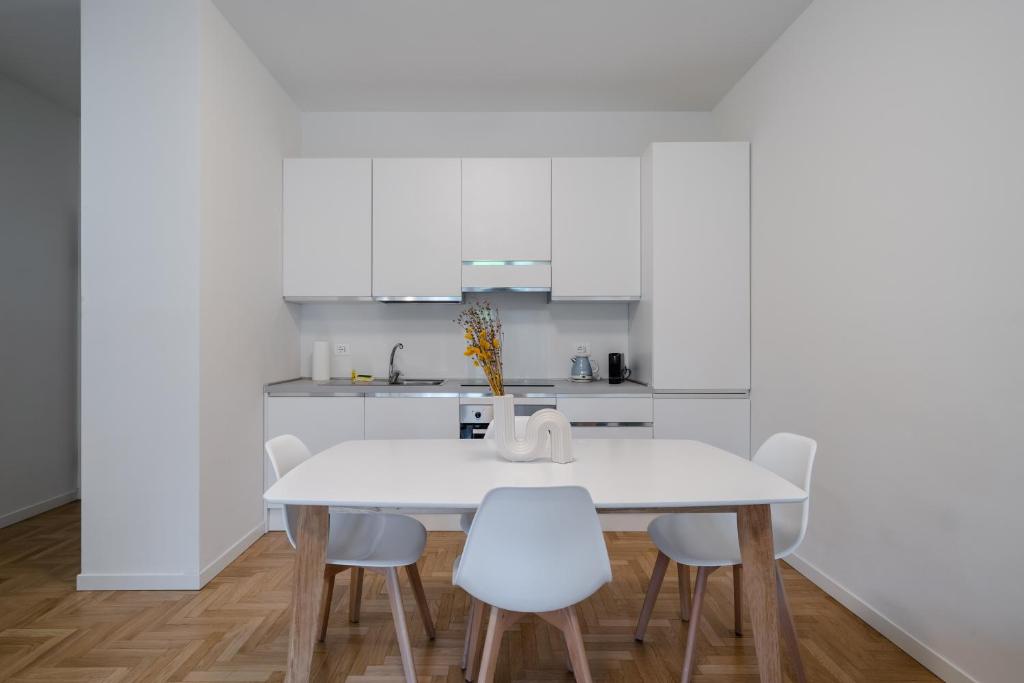 cocina blanca con mesa blanca y sillas en RELSTAY - CityLife - 2BR en Milán