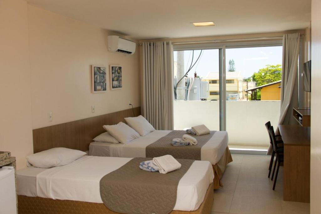 a hotel room with two beds and a window at Belluno Apart Hotel in Florianópolis