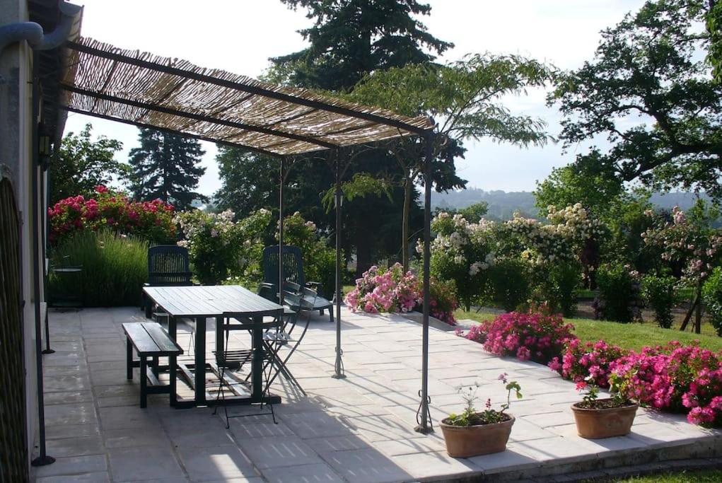 a patio with a table and chairs and flowers at La Maison des Roses in Mareuil-sur-Lay