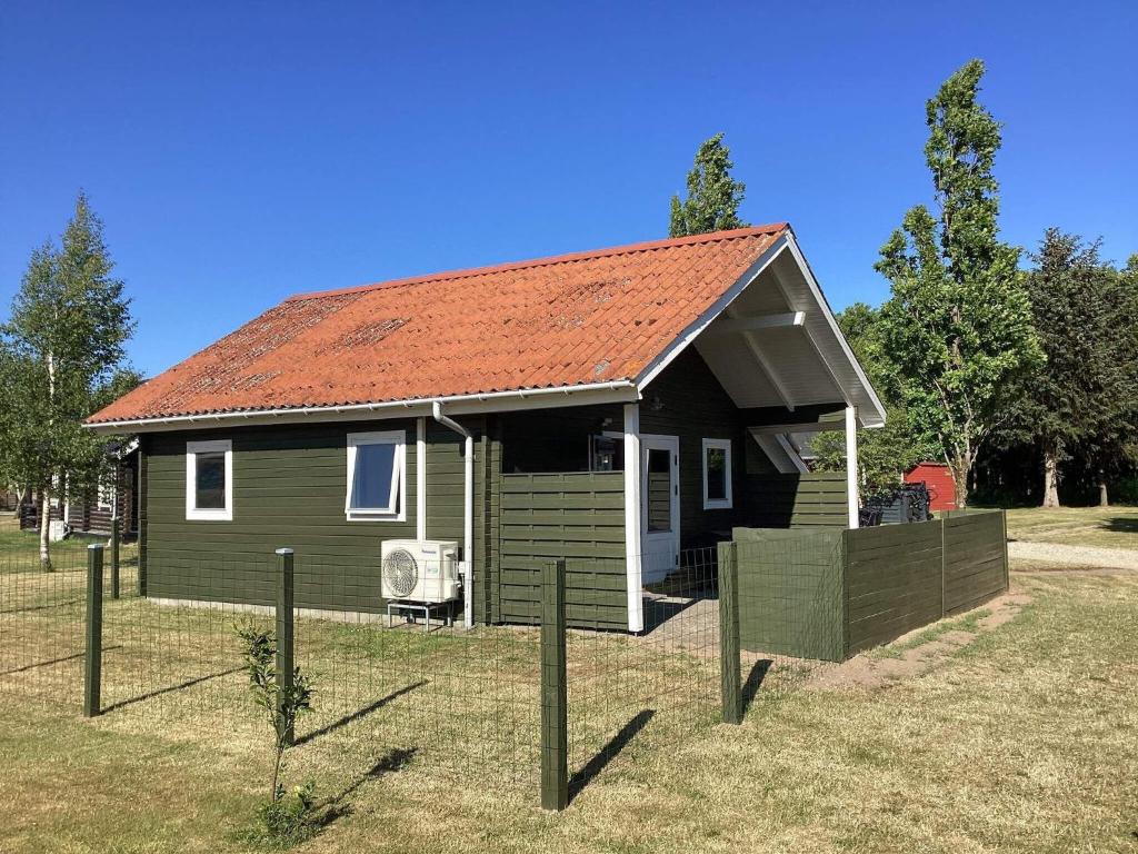 ein kleines grünes Haus mit orangefarbenem Dach in der Unterkunft Holiday home Hovborg XII in Hovborg