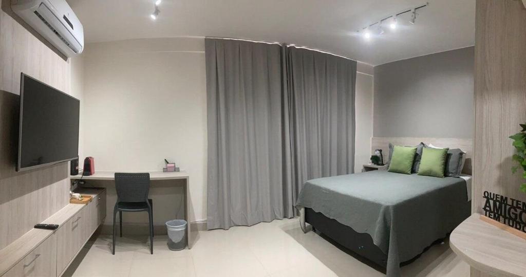 a bedroom with a bed and a desk and a television at Flat Noroeste Square by CentoEdez in Brasília