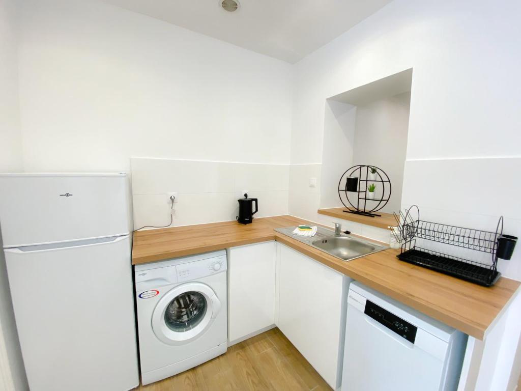 a kitchen with a white refrigerator and a washing machine at Les Dunes 1 in Sangatte