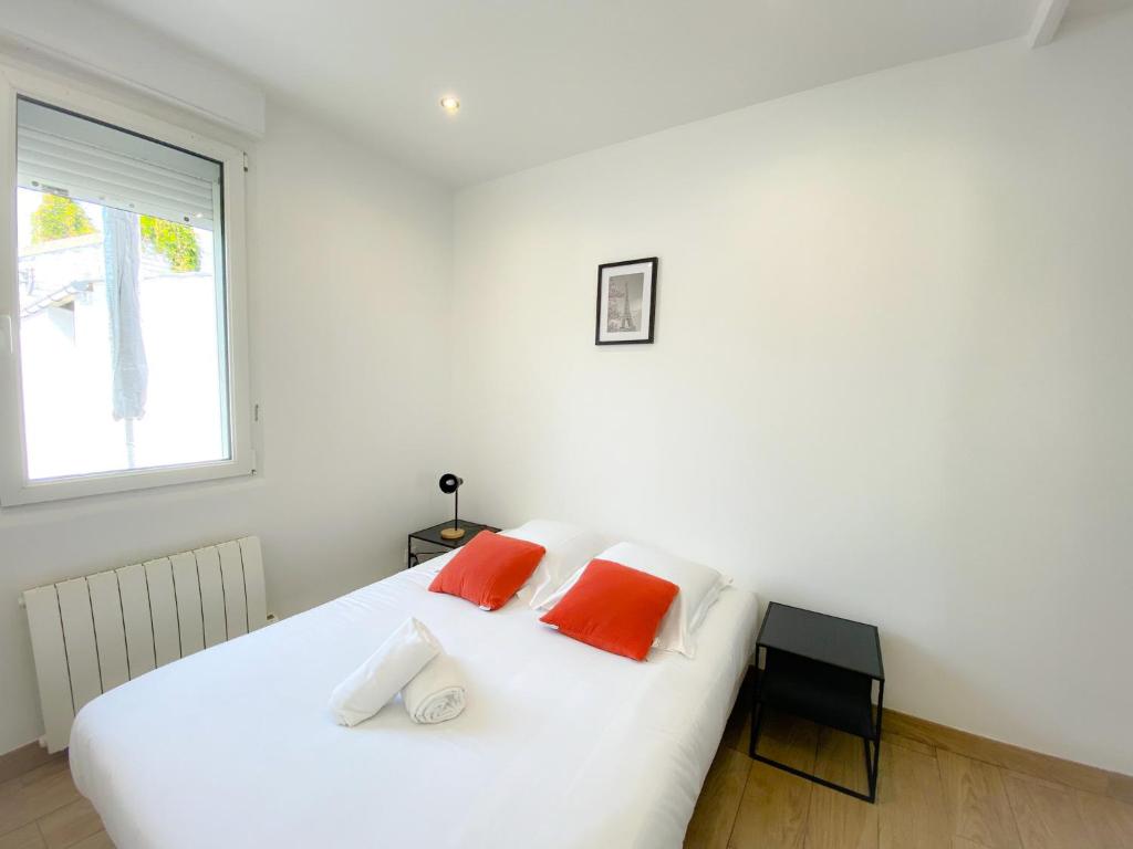 a bedroom with a white bed with two orange pillows at Les Dunes 1 in Sangatte