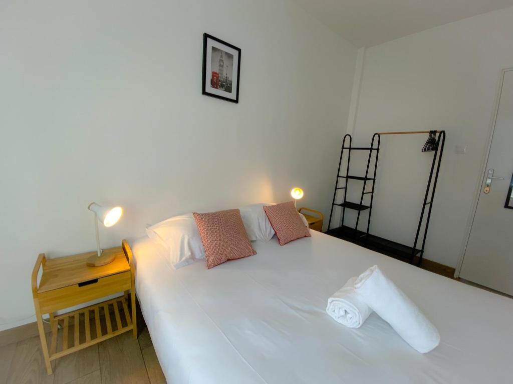 a bedroom with a large white bed with a night stand at Les Dunes 1 in Sangatte